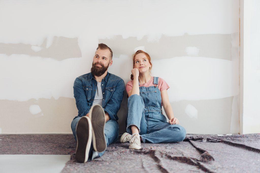 Couple qui se pose des questions assis dans une maison vide