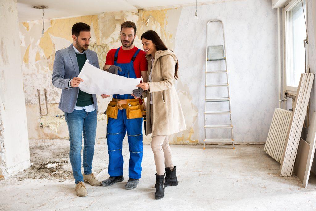 Couple avec un constructeur immobilier regardant un plan de leur maison en chantier
